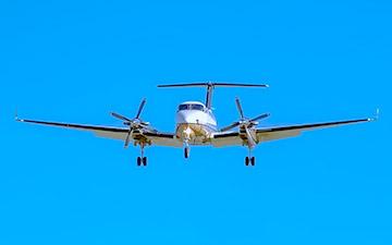 Private jet flying against a bright blue sky